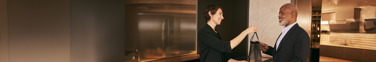 Two people interacting with a modern elevator in a well-lit lobby.